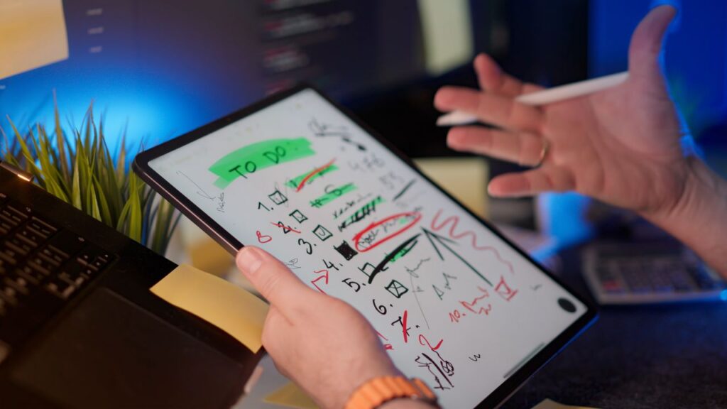 pexels photo 34213081 A person managing tasks on a tablet with a digital pen in a modern office setting.